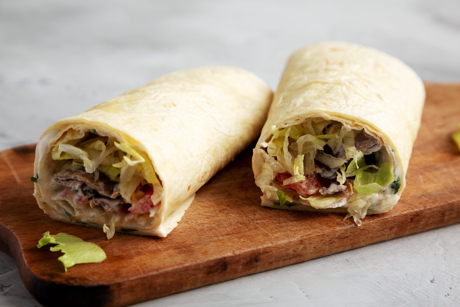 Two burrito halves on a wooden board.